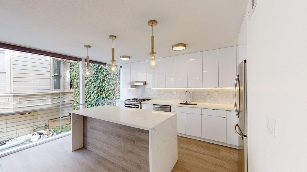 a kitchen with white cabinets and a large window