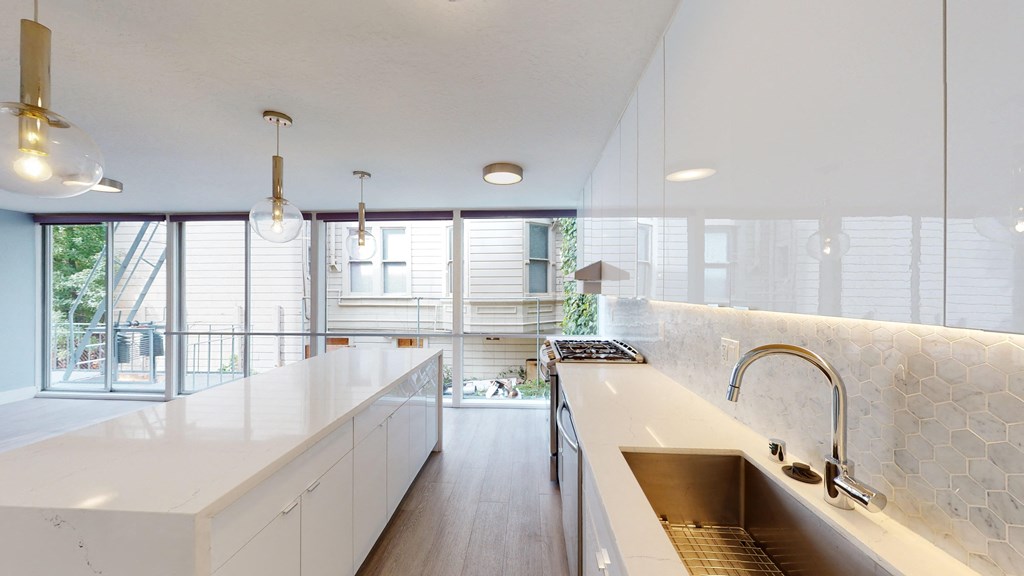 a large kitchen with white counter tops and a large sink