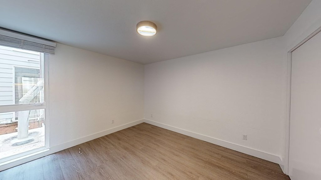 a living room with white walls and wood flooring and a window