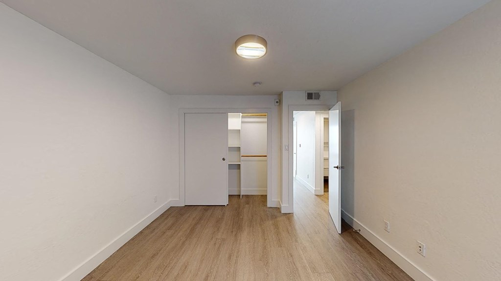 a living room and hallway with white walls and wood floors