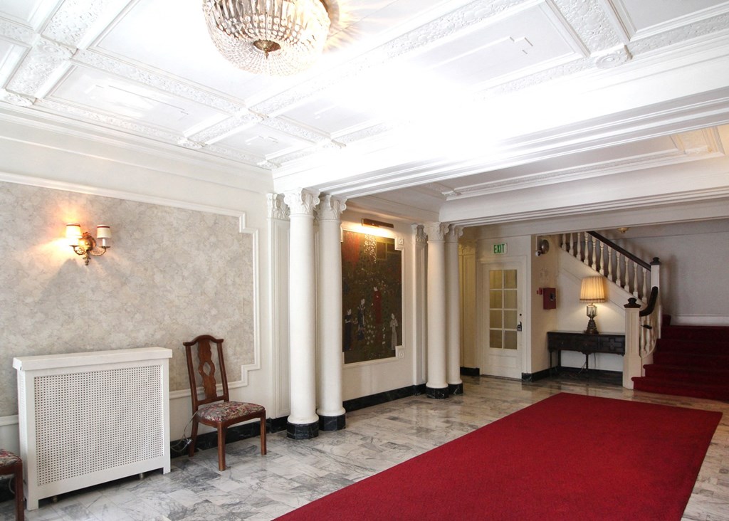 a lobby with a red carpet and pillars and a staircase