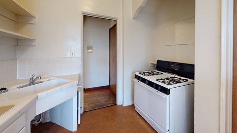A white kitchen with a stove and sink.