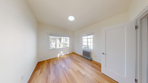 a living room with white walls and wood floors and a white door