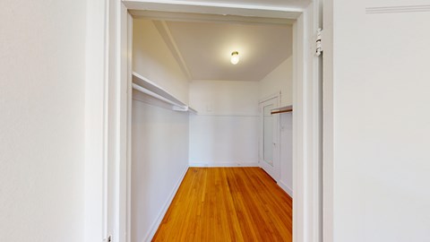 A hallway with a wooden floor and white walls.
