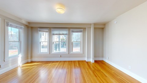 A room with wooden floors and three windows.