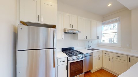 A kitchen with a stainless steel refrigerator and a stove top oven.