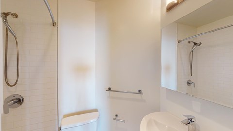 A white bathroom with a shower, toilet, and sink.