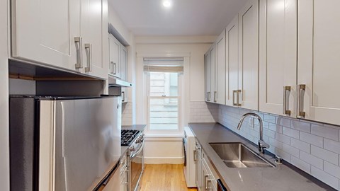 A kitchen with white cabinets and a stainless steel refrigerator.