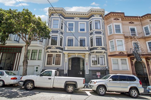 A row of colorful houses with cars parked in front.