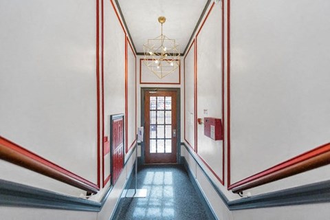 A hallway with a chandelier and a door at the end.