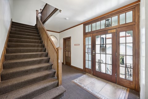Hallway with a wooden staircase and banister, a wooden door with glass window