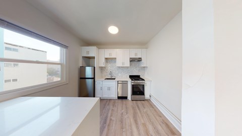 A kitchen with white cabinets and a wooden floor.
