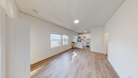 A spacious room with wooden floors and white walls.