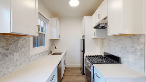 A kitchen with white cabinets and a stone backsplash.