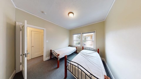 A bedroom with two beds and a window.