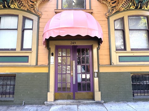 The building has a purple door and a pink awning.