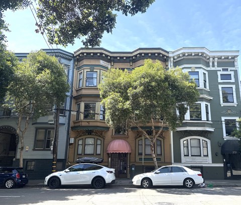 Two cars parked in front of a row of colorful buildings.