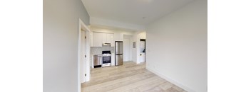 a renovated living room and kitchen with white walls and wood floors