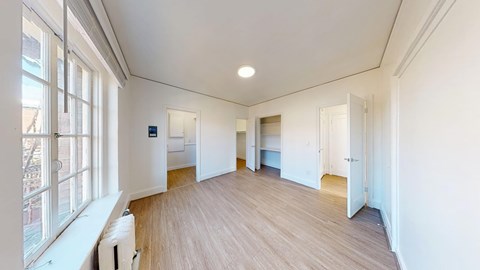 A spacious room with wooden floors and white walls.