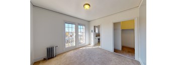 an empty living room with two windows and a door to a hallway