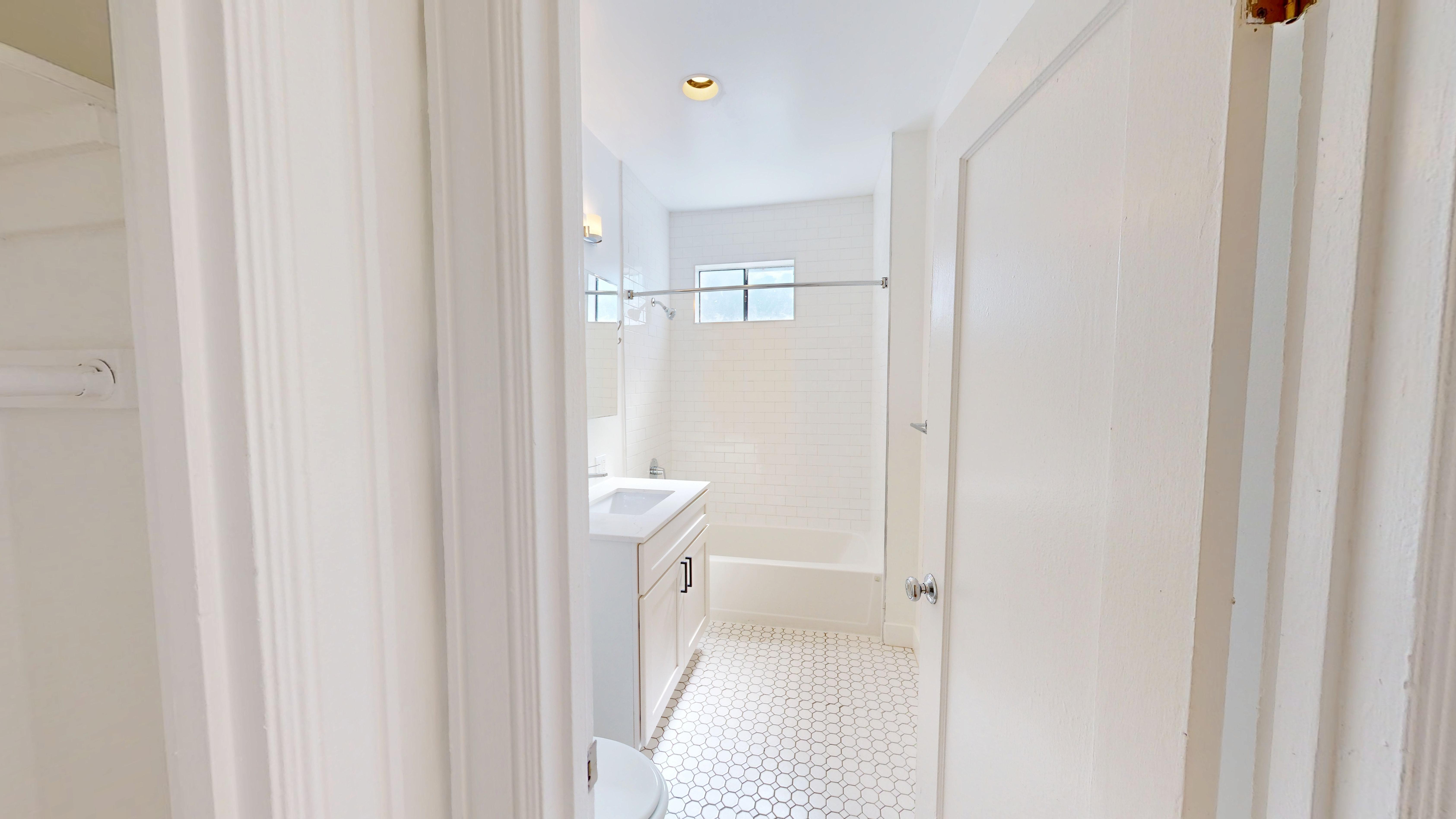 A white bathroom with a toilet, sink, and shower.