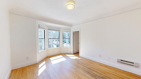 A room with wooden floors and a window overlooking a cityscape.