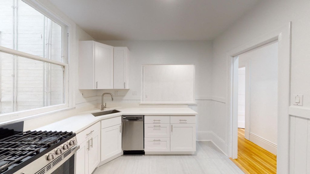 a white kitchen with a stove and a window