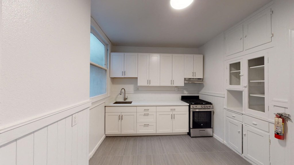 a white kitchen with white cabinets and a black stove