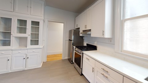 A kitchen with white cabinets and a black stove top oven.