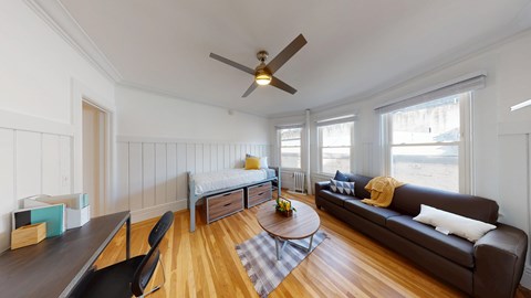 A living room with a brown couch, a coffee table, and a ceiling fan.
