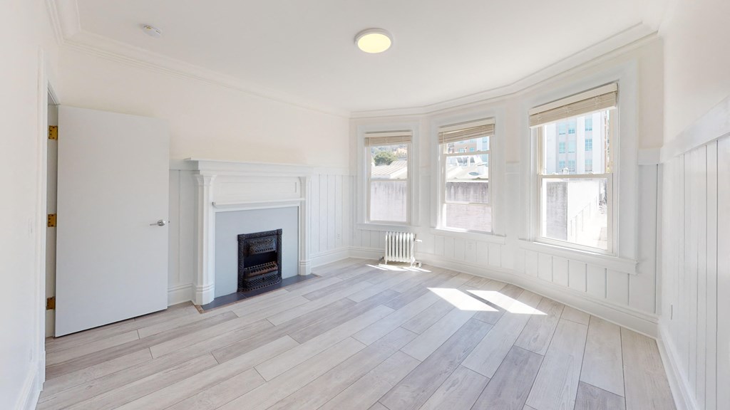 a living room with a fireplace and white walls and wood floors