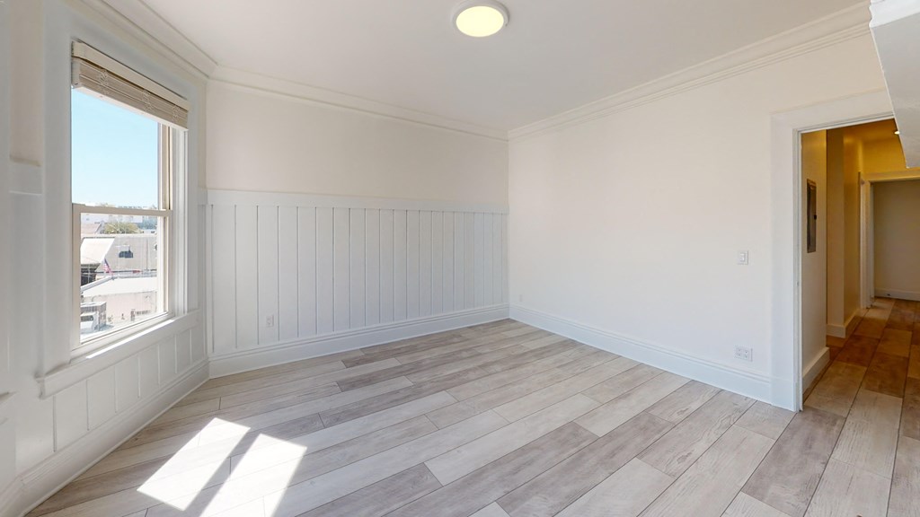 a living room with white walls and wood flooring and a window