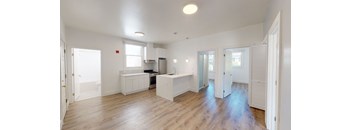 a renovated living room and kitchen with white walls and wood floors