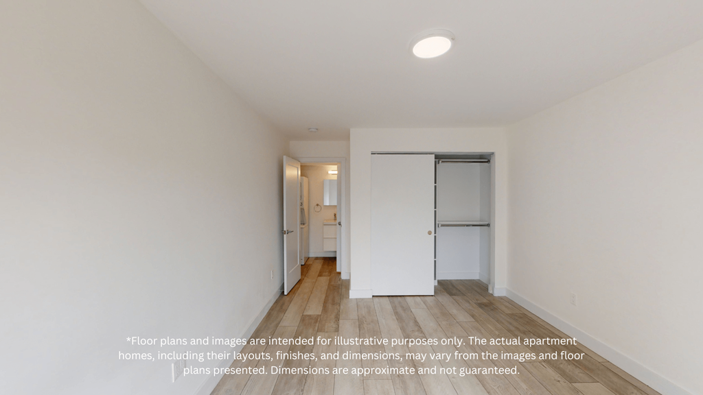 a room with white walls and wood floors and a hallway with a door to a