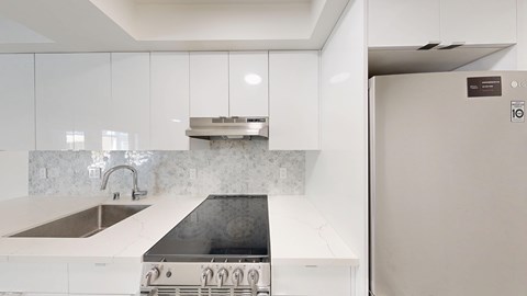 A modern kitchen with a white countertop and a black stove top.