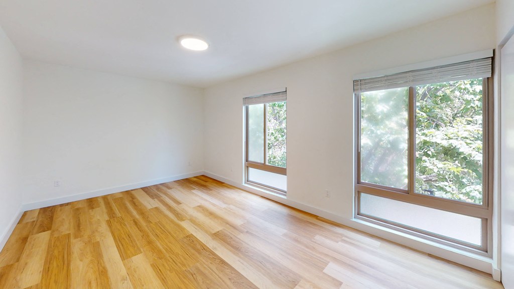 an empty living room with wood floors and large windows