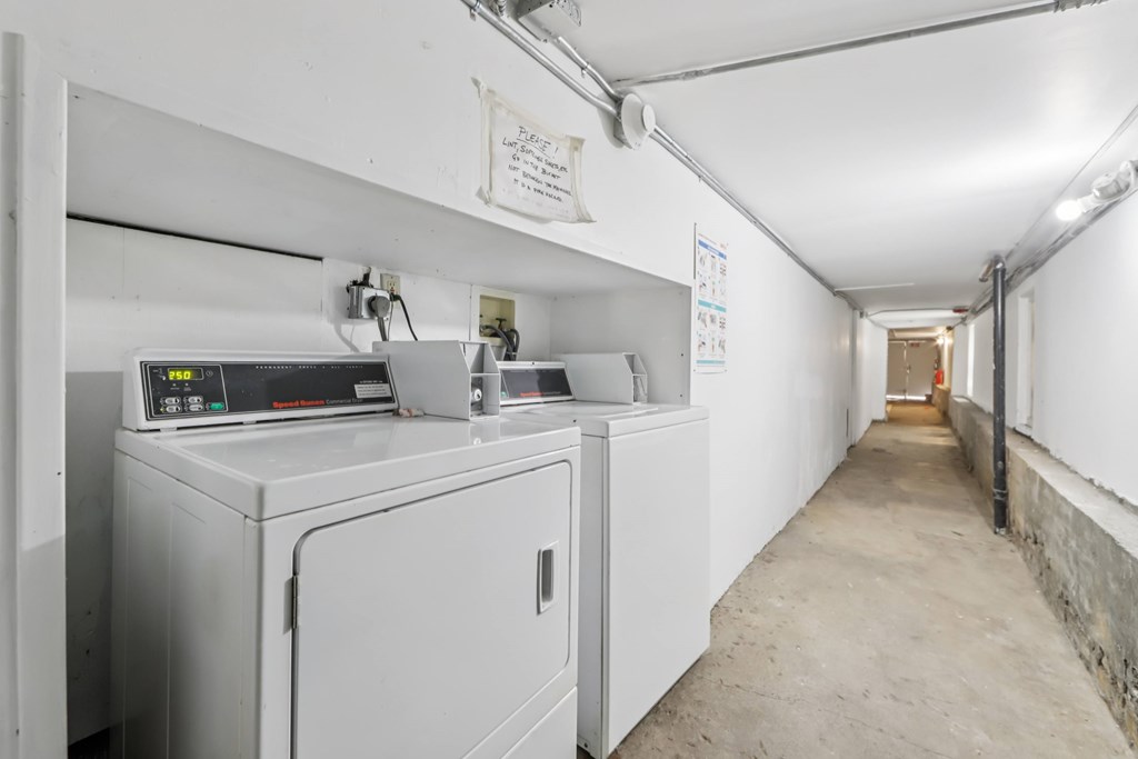 A long white hallway with a washing machine on the left.