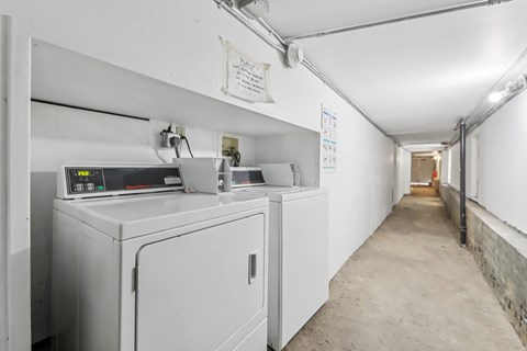 A long white hallway with a washing machine on the left.