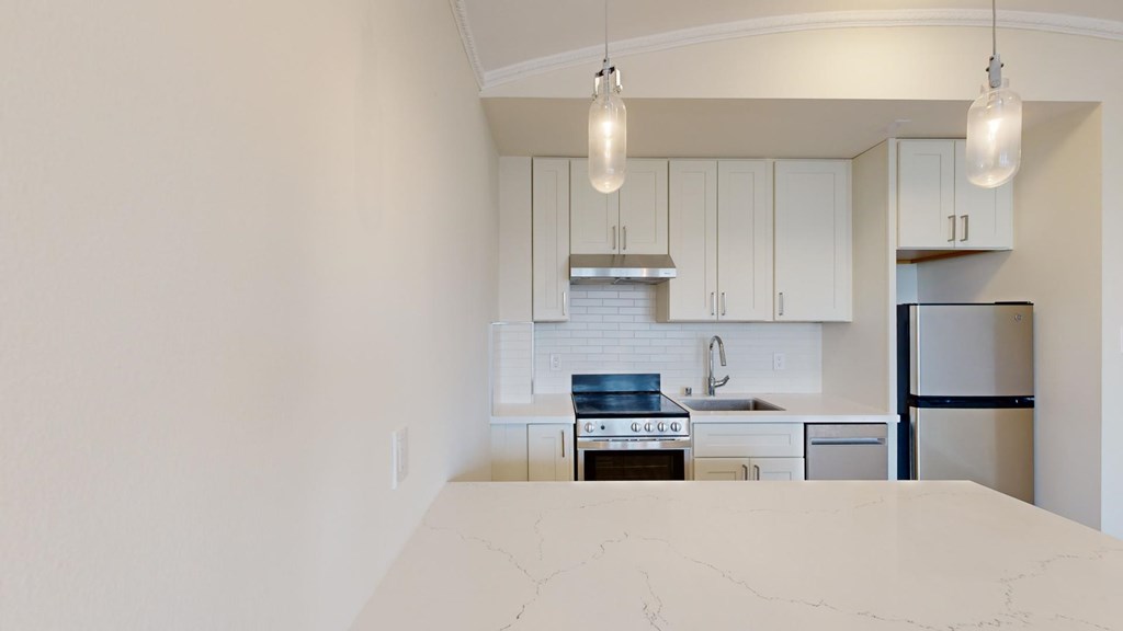 A kitchen with white cabinets and a marble countertop.