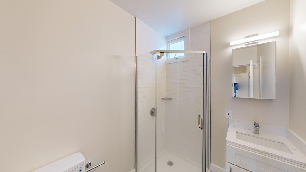A white bathroom with a toilet, sink, and shower.