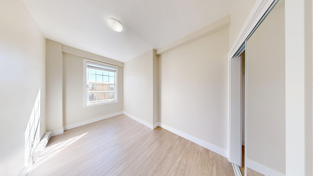 A room with a window and wooden flooring.