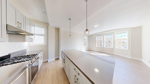 A modern kitchen with a stove top oven and a long counter top.