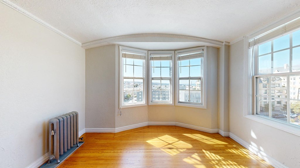 an empty living room with a radiator and three windows
