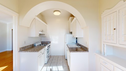 A kitchen with white cabinets and granite countertops.