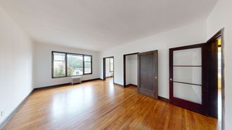 an empty living room with wood floors and white walls