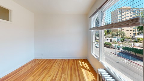 A room with wooden floors and a window overlooking a street.