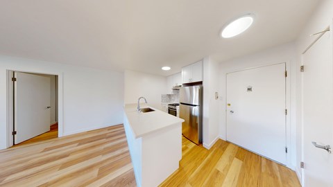 A kitchen with a white counter and wooden floors.