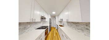 a large white kitchen with white cabinets and wood floors
