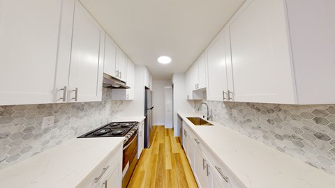 a large white kitchen with white cabinets and wood floors