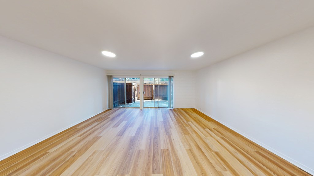 a living room with a wooden floor and a glass door